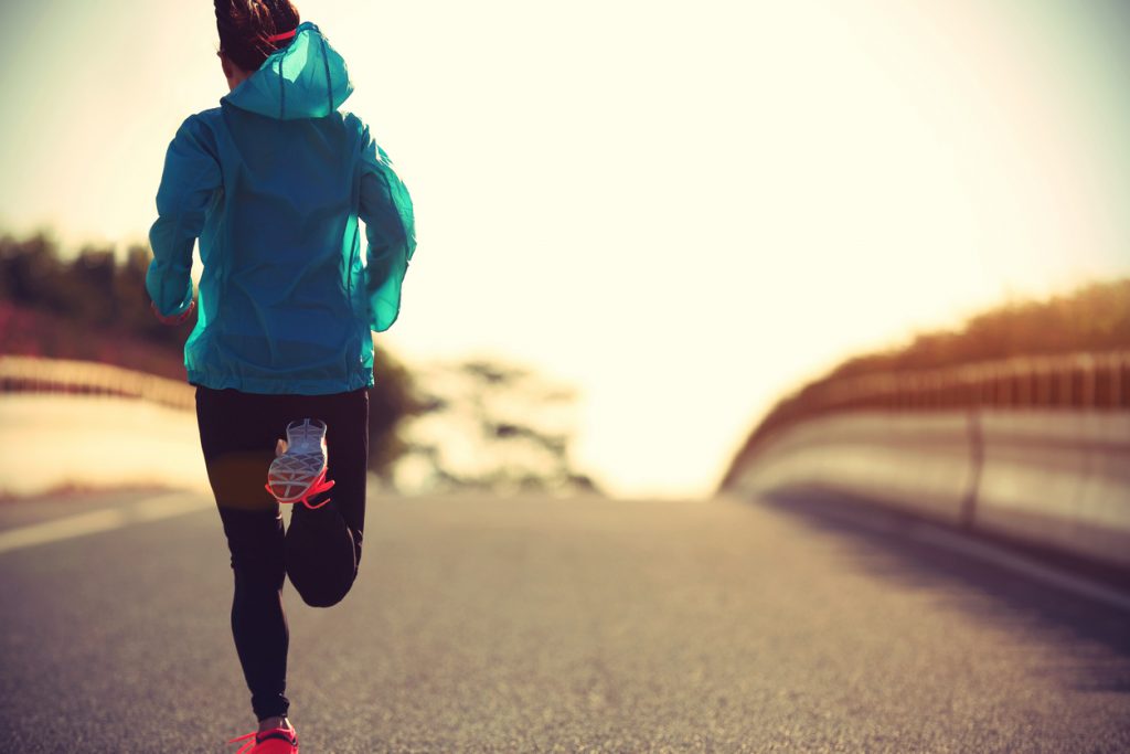 Built By She. A young fitness woman runner running on sunrise road