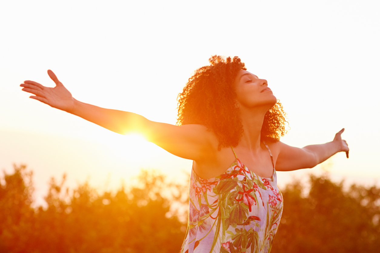 Built By She- Avocado Beautiful mixed race woman expressing freedom on a summer evening outdoors with her arms outstretched